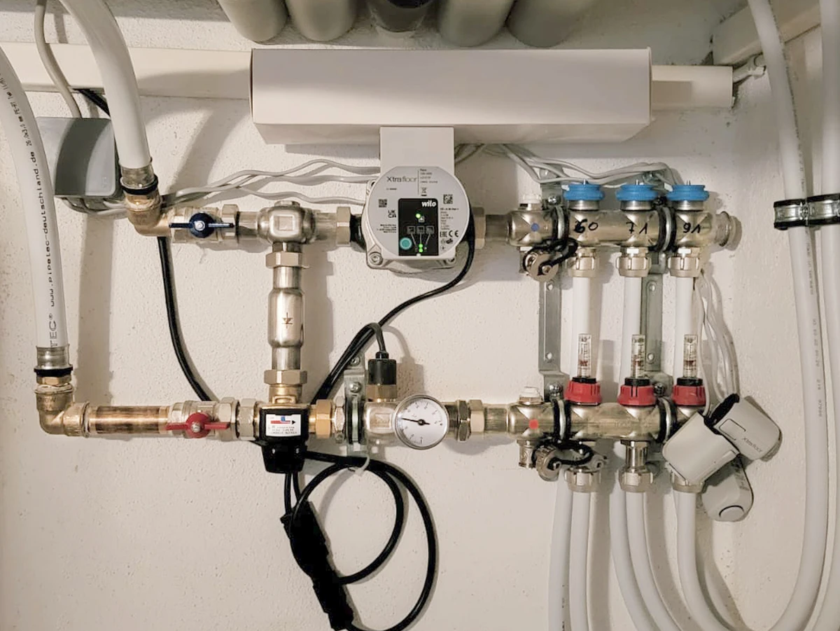 Heizungsinstallation mit Wasseranschluss, Absperrventilen, Verteilerblock, Messmodul und verschiedenen Heizungsrohren