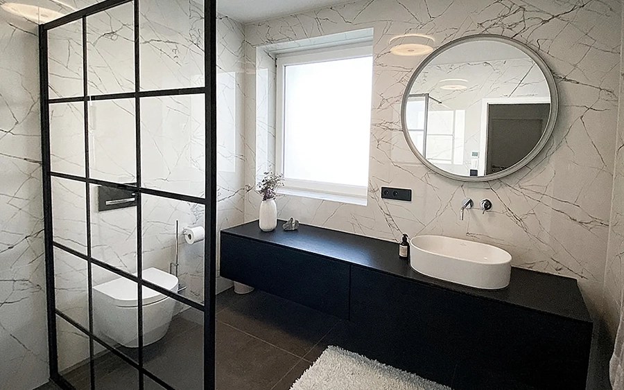 Bad renovieren Firma – ALLSAN Referenzprojekt edles Badezimmer mit deckenhohen und fugenlosen Riesen-Fliesen sowie großer schwarzer Waschtisch mit elegantem grifflosem push-to-open System über die gesamte Raumbreite